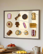Framed artwork of various cookies on a kitchen counter with food items.