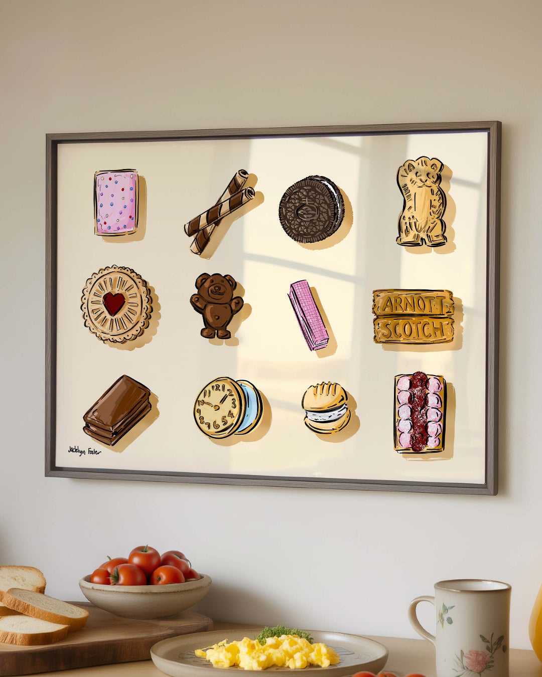 Framed artwork of various cookies on a kitchen counter with food items.