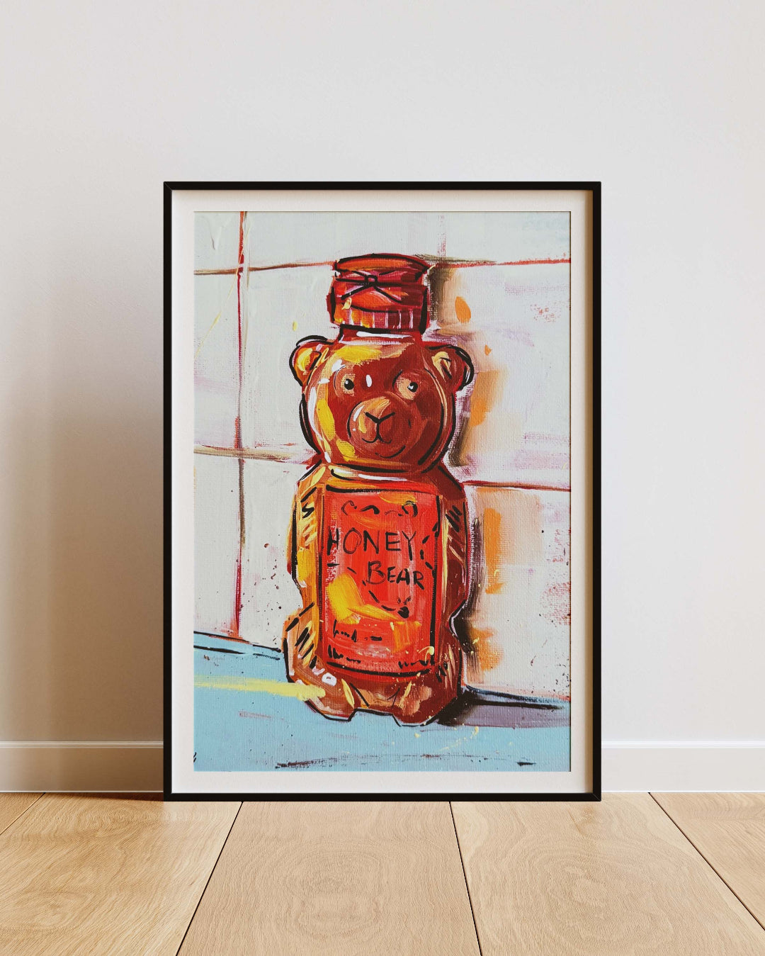 Framed artwork of a bear-shaped honey jar on a light wooden floor and white wall.